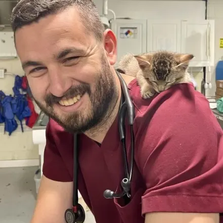 Dr. John Komlosy in red scrubs and kitten on back.